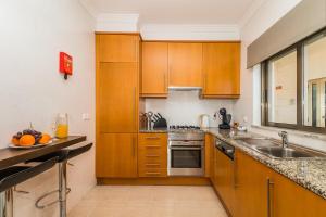 a kitchen with wooden cabinets and a sink at Vandalou By ALzira in Albufeira