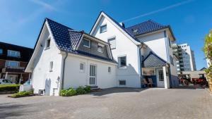 a white house with a blue roof at Haus Meereswoge, Duhnen in Cuxhaven