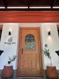 a wooden door in a building with two plants at Villa del Vino in Mikrós Prínos
