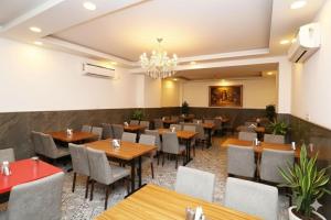 a restaurant with wooden tables and chairs and a chandelier at Hotel The New Pacific Suites Near IGI Airport Delhi in New Delhi