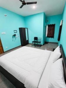 ein großes weißes Bett in einem Zimmer mit blauen Wänden in der Unterkunft Prasant Inn in Bhubaneshwar