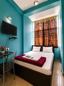ein Schlafzimmer mit blauen Wänden und einem Bett mit Fenster in der Unterkunft Prasant Inn in Bhubaneshwar