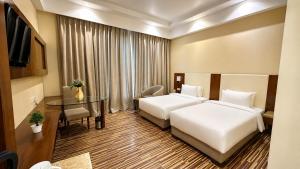 a hotel room with two beds and a table at Golden Tulip Kukas Jaipur in Jaipur
