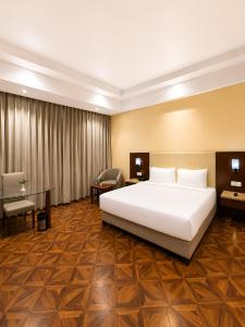 a hotel room with a large bed and a desk at Golden Tulip Kukas Jaipur in Jaipur