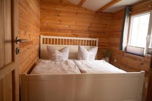 a bedroom with a white bed in a wooden room at Ferienhaus Wasserläufer Bellin in Ueckermünde