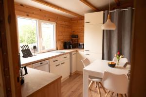 a kitchen with white cabinets and a table with chairs at Ferienhaus Wasserläufer Bellin in Ueckermünde +13 photos