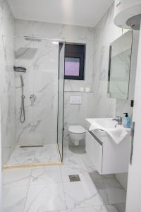 a white bathroom with a shower and a toilet at Nejla Apartmani Stoj in Ulcinj +24 photos