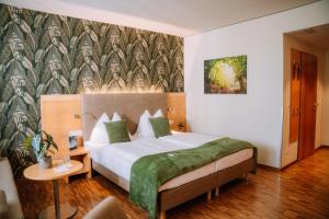 a bedroom with a large bed with a green blanket at Hotel Auszeit St Lambrecht in Sankt Lambrecht +91 photos