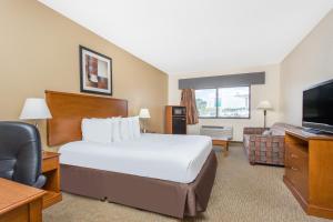 a hotel room with a bed and a flat screen tv at Days Inn By Wyndham Phenix City Near Fort Moore in Phenix City