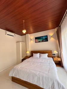 a bedroom with a large bed with a wooden ceiling at KUTA GLORI Homestay in Kuta Lombok