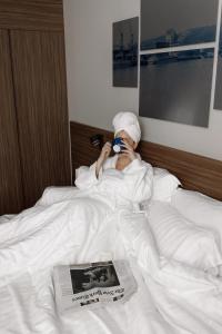 a person laying in bed drinking from a cup at Radisson Blu Hotel, Rouen Centre in Rouen
