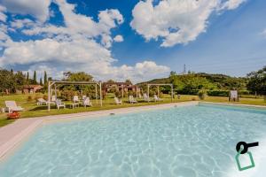 a large swimming pool in a yard with chairs at Hotiday Massa Marittima in Massa Marittima