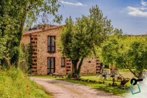 a stone house with trees and a dirt road at Hotiday Massa Marittima in Massa Marittima