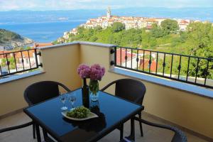 a table with wine glasses and flowers on a balcony at Apartmani Marin1 in Vrbnik