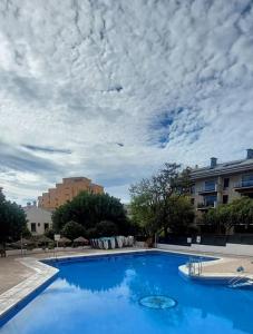 a large blue swimming pool under a cloudy sky at Luis Vives in Benalmádena
