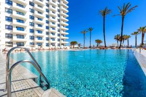 a large swimming pool with palm trees and a building at Ocean House Costa del Sol apartamentos varios by Costa del Sol Stay in Torremolinos