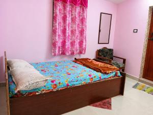 a bedroom with a bed with a floral bedspread at Comfort Cottage in Yercaud