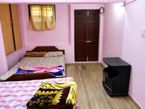 a small room with two beds and a door at Comfort Cottage in Yercaud
