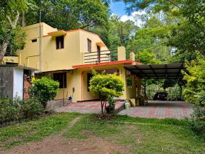 a yellow house with a driveway in front of it at Comfort Cottage in Yercaud