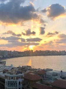 a sunset over the water with a city at New Hyde Park House Hotel in Alexandria