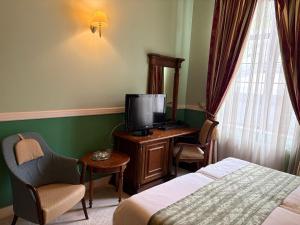 a hotel room with a bed and a desk with a television at Angelo Doro Hotel in Ploieşti