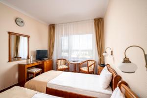 a hotel room with two beds and a desk and a television at Hotel Traian in Brăila +50 photos