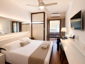 a bedroom with a white bed and a ceiling fan at Piccolo Hotel in Castiglione della Pescaia