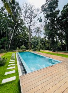 a swimming pool in a yard with a wooden deck at Wimala Sewana in Veyangoda