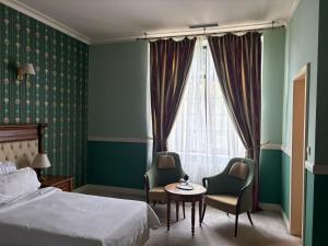 a bedroom with a bed and two chairs and a table at Angelo Doro Hotel in Ploieşti