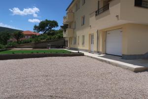 a house with a garage and a gravel driveway at Apartmani Marin1 in Vrbnik