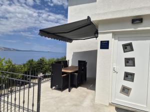 a patio with a table and a black umbrella at Apartmani Silvana&Vera in Senj