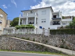 a white building behind a stone retaining wall at Apartmani Silvana&Vera in Senj