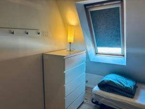 a bedroom with a dresser with a lamp and a window at Søgården, 3080 Tikøb in Tikøb