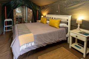 a bedroom with a bed with yellow pillows at Die Fonteine Country Guesthouse and Glamping in Oudtshoorn