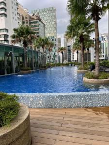 a large swimming pool with palm trees in a city at VORTEX Suites KLCC Premium BY RRP in Kuala Lumpur