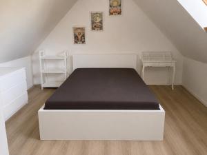 a bedroom with a white bed with a black mattress at BLTN House in Balatonalmádi
