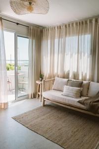 a living room with a couch and a large window at Apartamentos Eugenio by Formentera Passport in La Savina