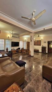 a living room with a couch and a ceiling fan at Manasthala Brindavan in Mysore
