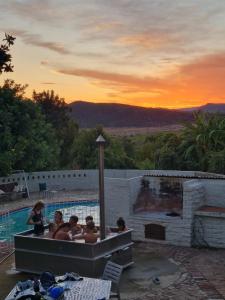 a group of people sitting around a swimming pool at Doornkraal Farm in De Rust