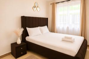 a bedroom with a bed with a black headboard and a window at Stylish 2BR Apartment Free WiFi Near Nairobi National Park in Ongata Rongai 
