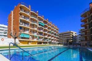 a swimming pool in front of a building at TECAVI III Apartamento in La Pineda