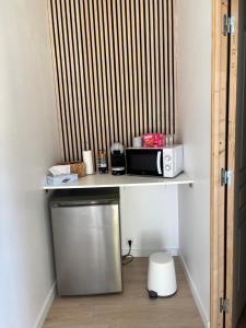 a kitchen with a shelf with a toaster and a microwave at Studio cosy avec accès jardin in Lunel-Viel