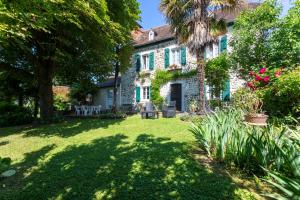 a garden in front of a house with a palm tree at L'Authentique Maison Béarnaise in Lagor