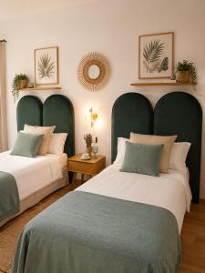two beds with green headboards in a bedroom at Hotel Temple Pradorrey in Astorga
