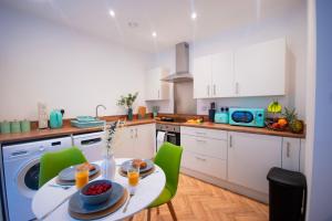 a kitchen with a white table and green chairs at Derby Luxury Apartments - Curzon in Derby +54 photos