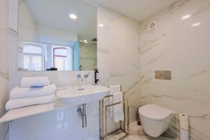 a white bathroom with a sink and a toilet at Casa da Portagem by PURUS in Coimbra +31 photos
