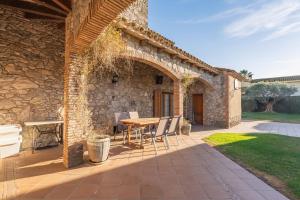 a stone house with a table and chairs on a patio at Cal Ferrer Nou Costa Brava in Riumors