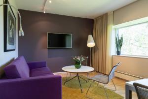 a living room with a purple couch and a table at Sørmarka Konferansehotell in Siggerud