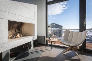 a living room with a white chair and a fireplace at One And Only Villas in Palaios Agios Athanasios