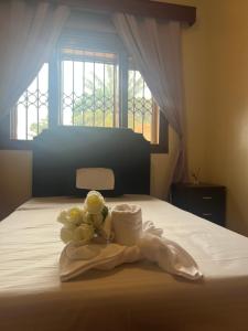 a bed with towels and flowers on it with a window at Happy Fish Villa in Entebbe